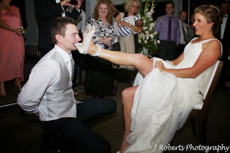 Groom using his teeth to take the brides garter off - wedding photography sydney